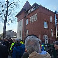 Vor der Kulturfuge Menschen stehen vor einem Backsteinhaus