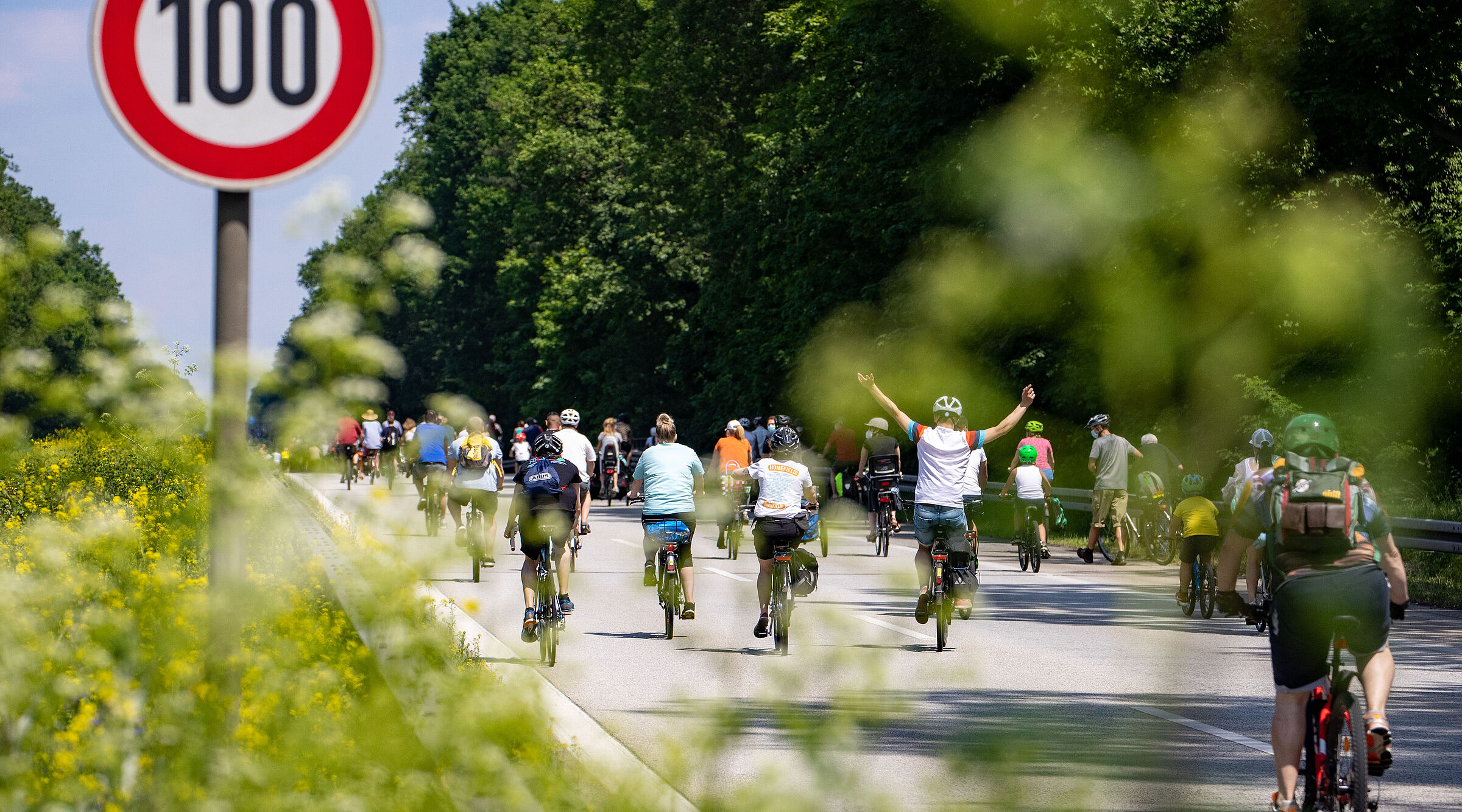 Radfahrer bei Sternfahrt neben Schild zu Geschwindigkeitsbegrenzung 100h/km
