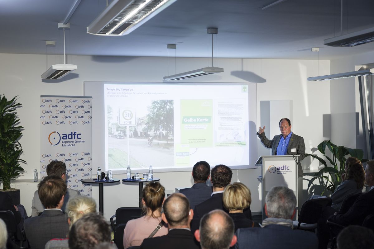 Jörg Jenoch Jörg Jenoch, Bürgermeister der Gemeinde Eichwalde, am Podium, hinter ihm die Leinwand mit einer projizierten Präsentation.